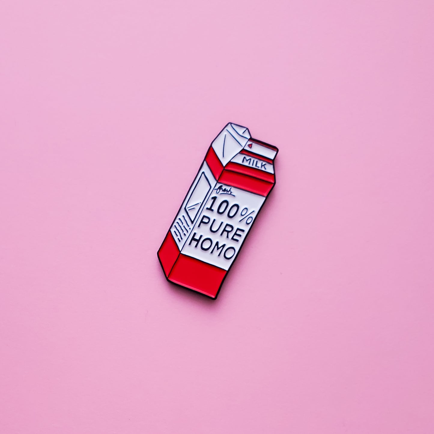 This red and white Milk-Carton shaped enamel pin features the words '100% pure homo' set on a pink background. Homo Milk Pin For Sale - LGBTQ Pride Pin Canada  | Little Rainbow Paper Co