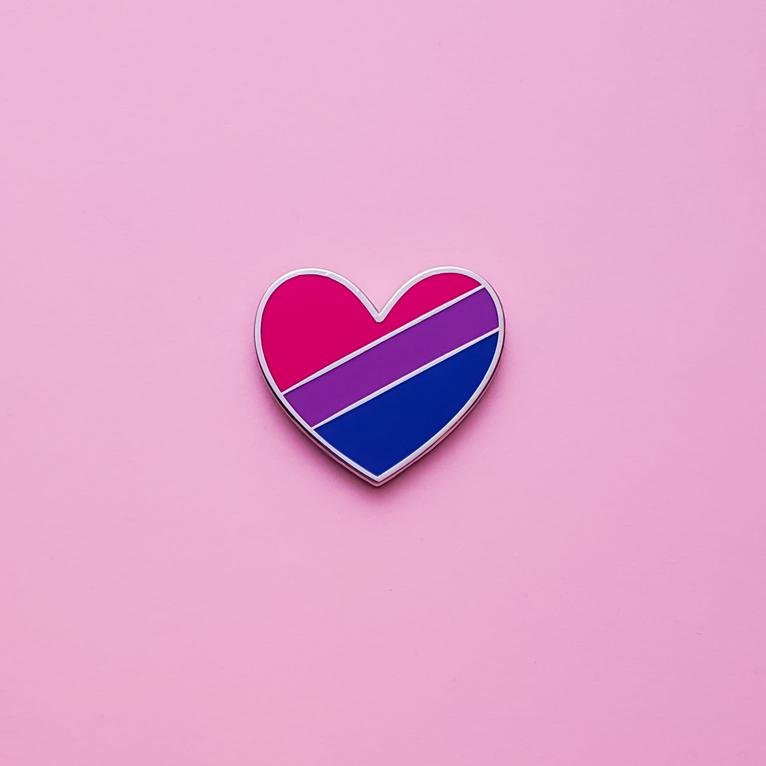 Bisexual Pride Heart Pin on a pink background. Pin is has vibrant bisexual pride colours set in a polished nickle metal. Bisexual pride pin colours are pink, purple and blue.Bi Heart Pin - LGBTQ Pride Pins | Little Rainbow Paper Co