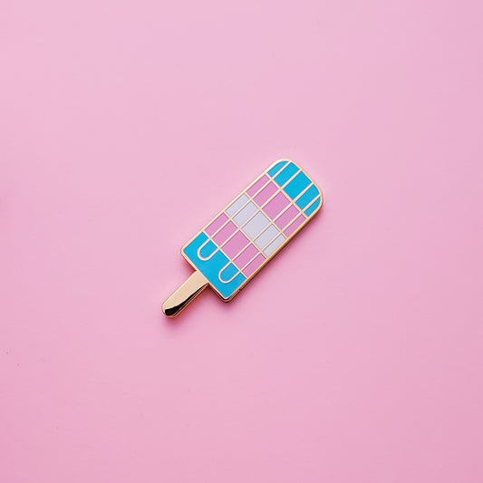 Popsicle-shaped Trans Pride Pin on a pink background. This Trans pin is has vibrant Transgender pride colours set in a polished gold metal. Trans pride pin colours are blue, pink and white.. Trans Popsicle Pin - LGBTQ Pins For Sale | Little Rainbow Paper Co