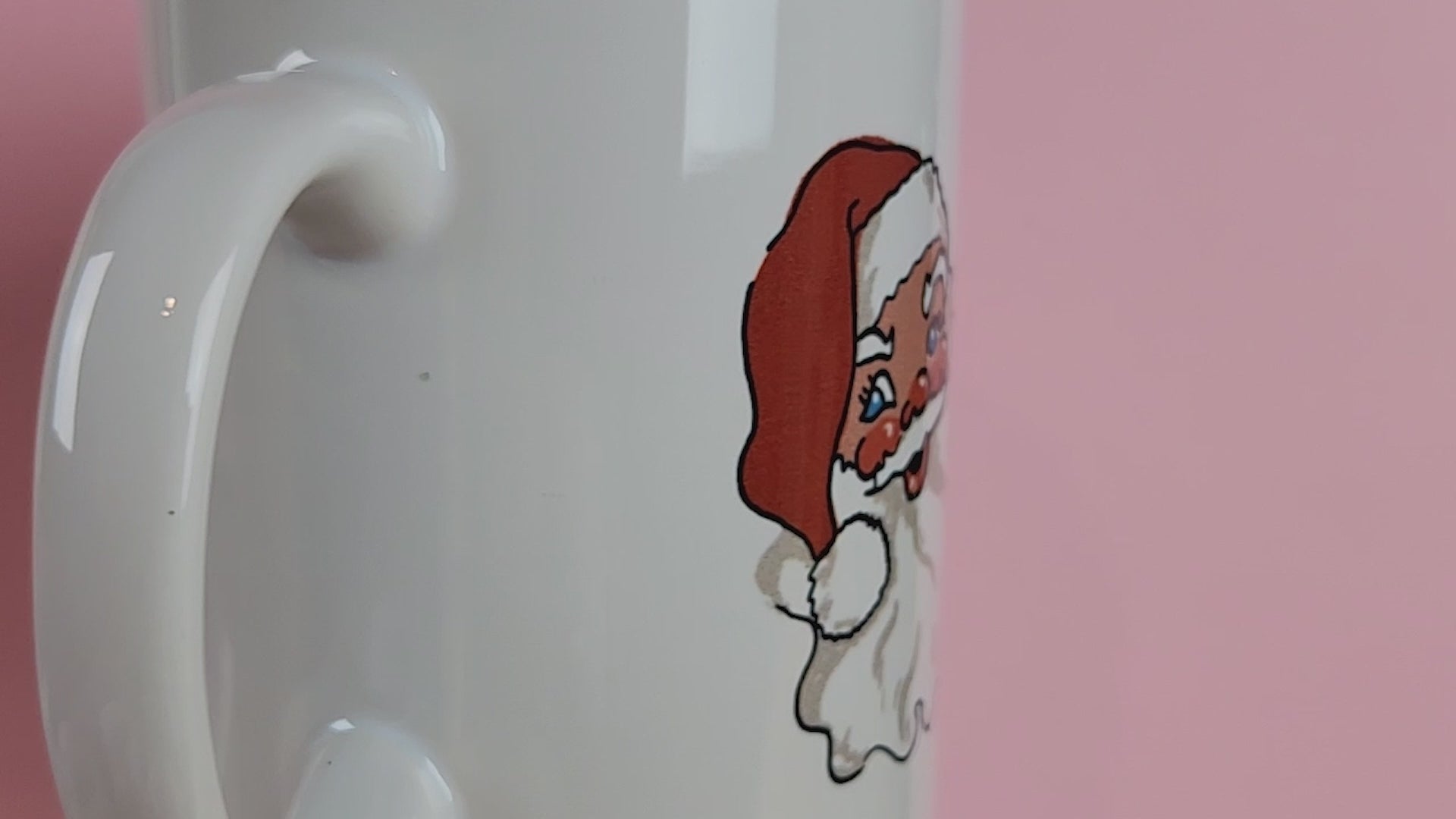 Video of a LGBTQ mug on pink background that reads Santa's Favourite Homo. A gay christmas mug