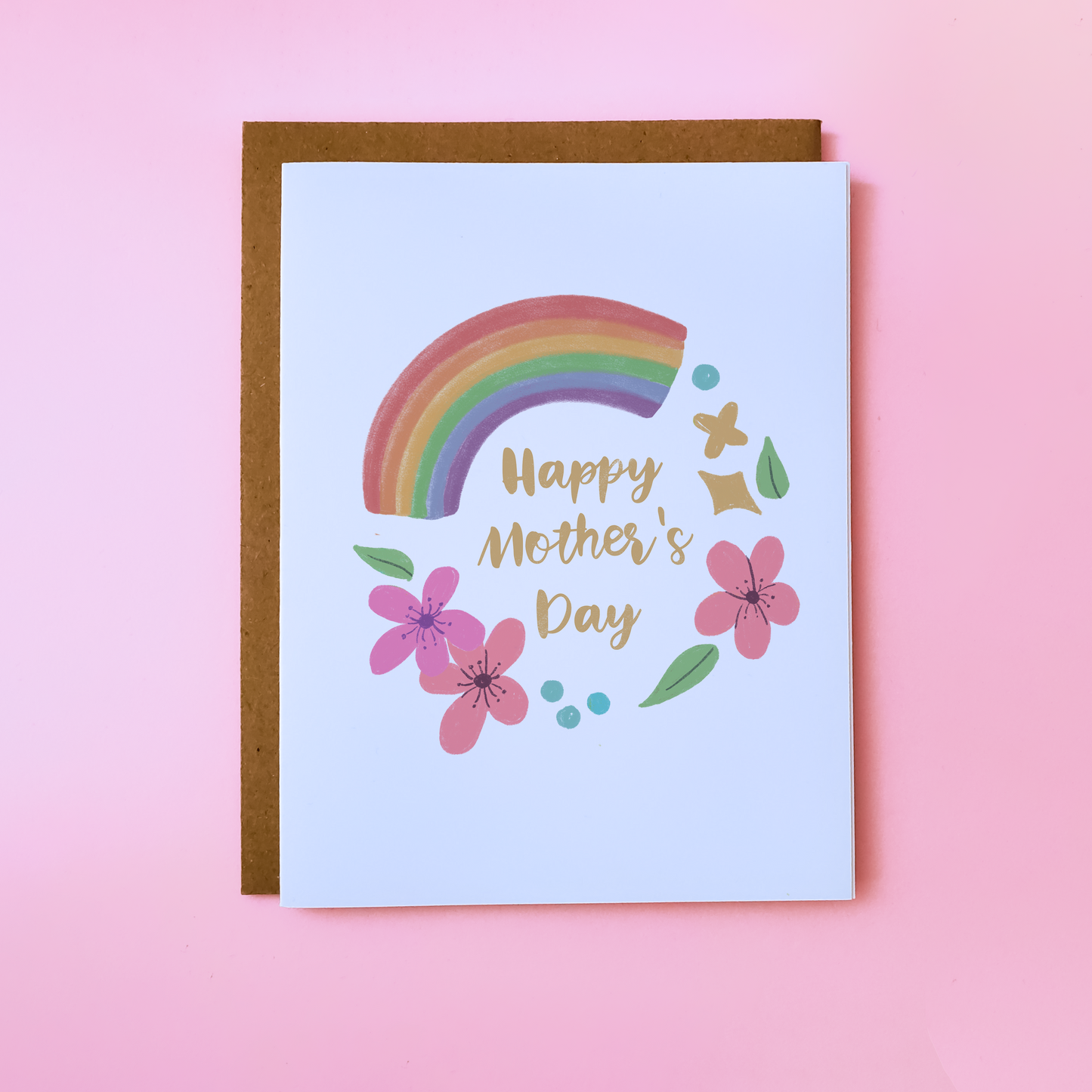 A LGBTQ Parent Card with a kraft envelope set on a pink background. This lgbtq Mother's Day Card features flowers and a rainbow and reads 'Happy Mother's Day'.