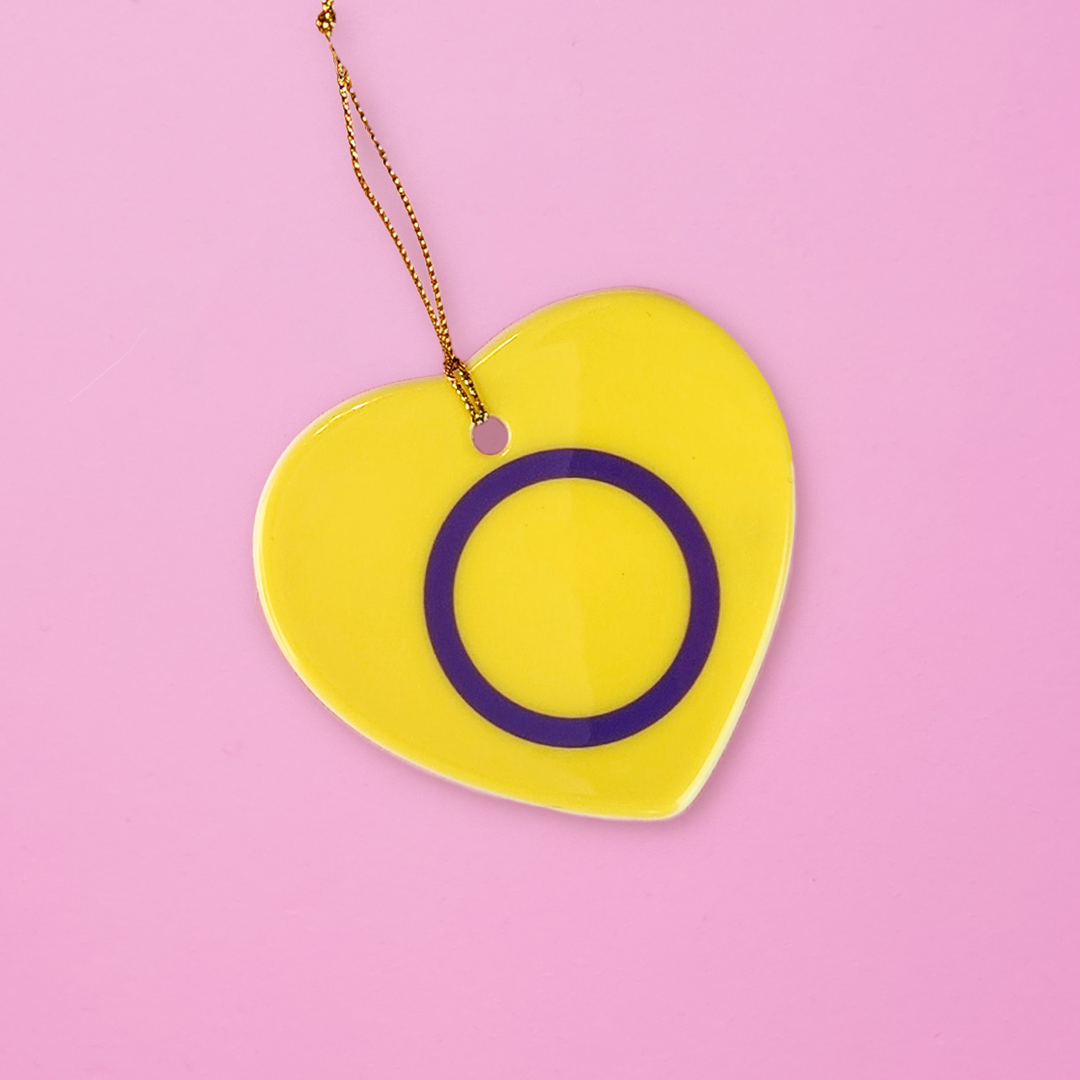 Ceramic heart shaped Intersex ornament with the intersex pride colors on a pink background. Heart Intersex pride ornament