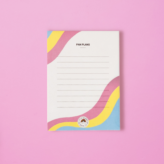 A LGTBQ notepad with the pan pride flag colors printed on the front. Text reads pan plans and has lines for writing. A cute pansexual pride notepad